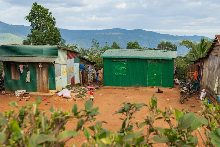 Colorful metal houses in a rural setting with mountain backdrop and a young child in vibrant clothing.