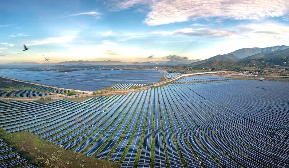 Aerial view of a vast solar farm with mountains and morning sky in Vietnam, symbolizing renewable energy.