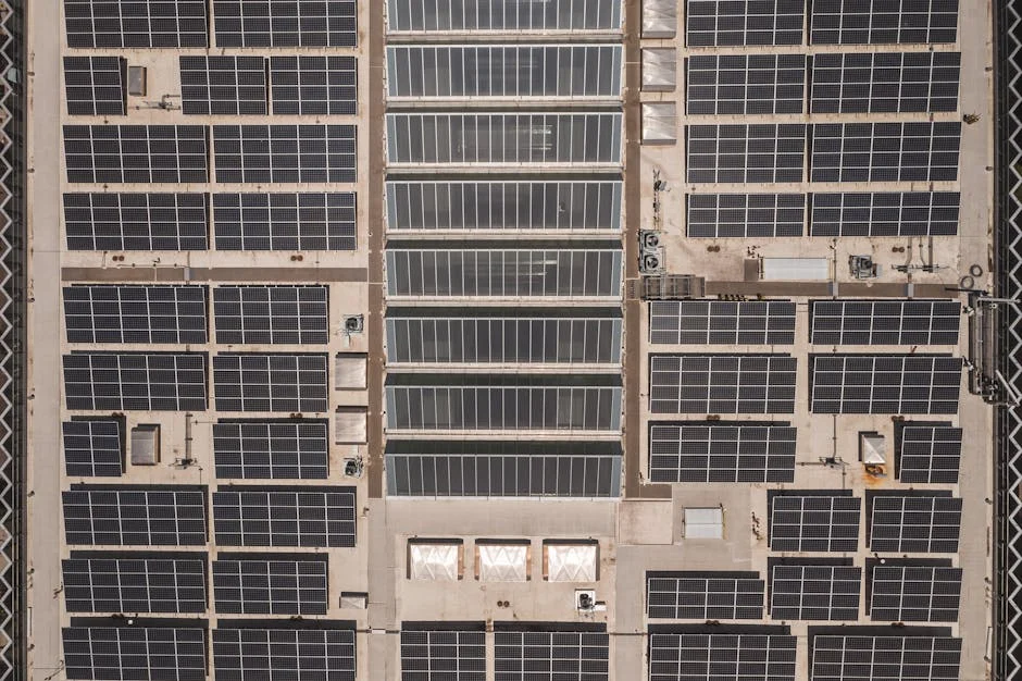 A high-angle drone shot capturing a grid of solar panels on a large industrial rooftop, showcasing renewable energy.